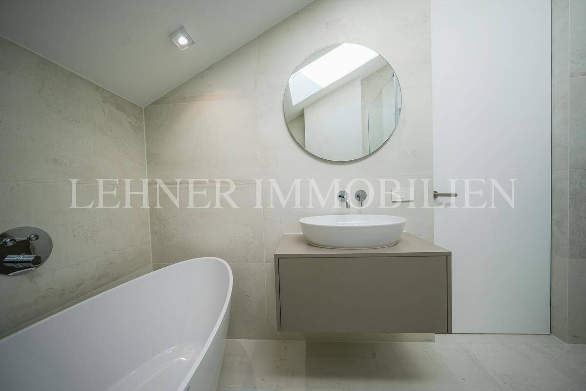 Stilvolles Badezimmer mit Waschtisch, rundem Spiegel und minimalistischem Design.
