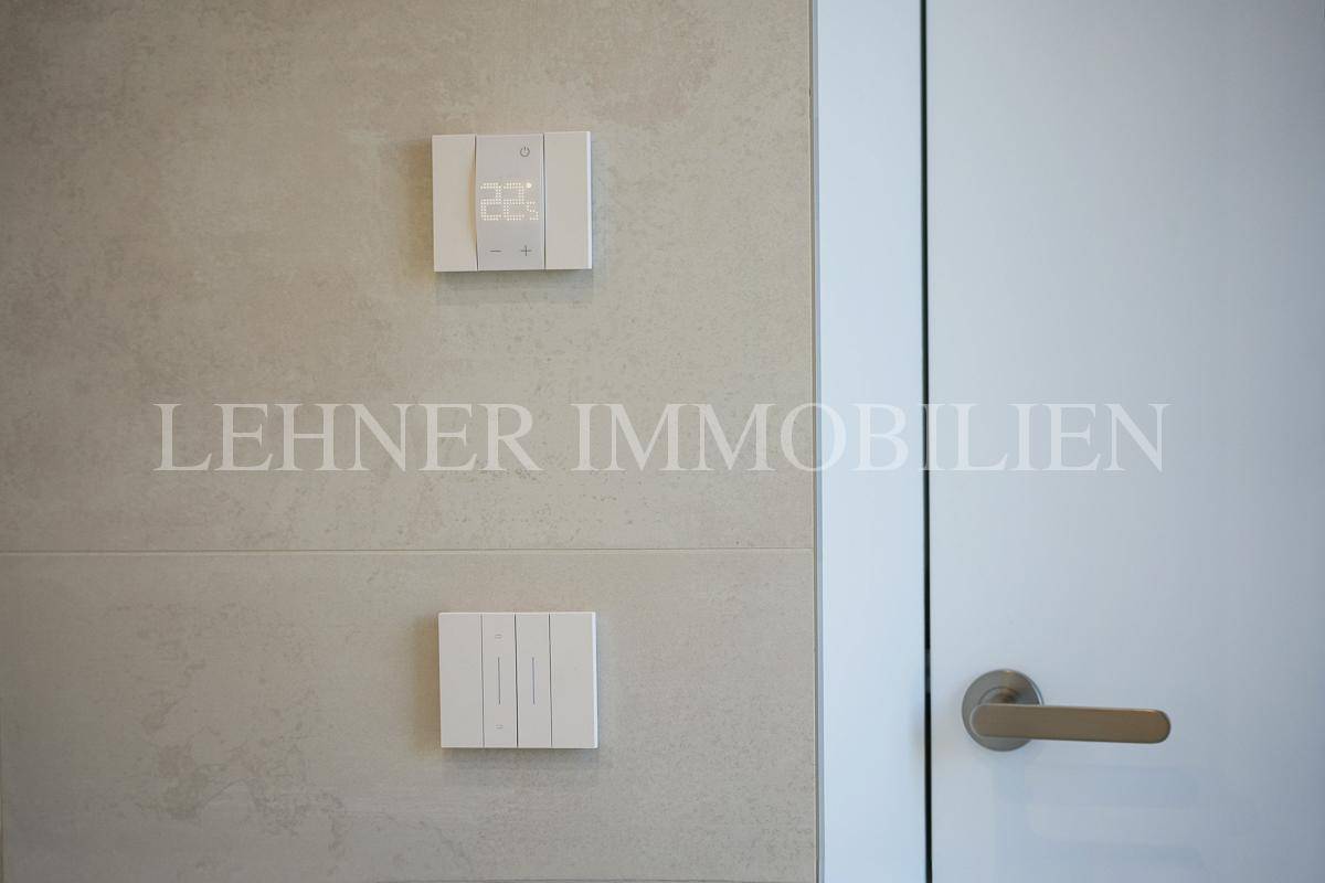 Moderne Lichtschalter und Thermostat an einer gefliesten Wand neben einer Tür.