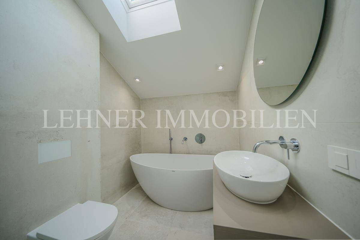 Modernes Badezimmer mit freistehender Badewanne, Waschtisch und Dachfenster.
