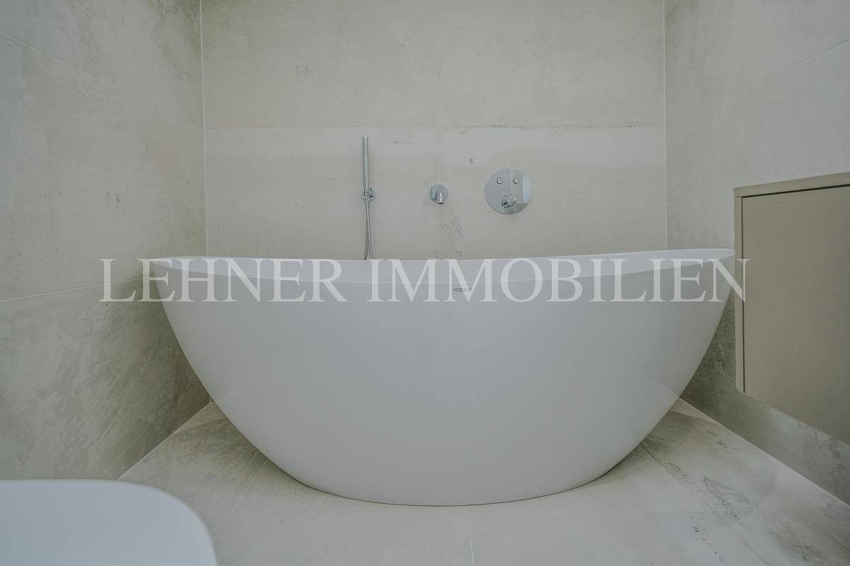 Freistehende Badewanne in einem modernen Badezimmer mit hellen Fliesen.