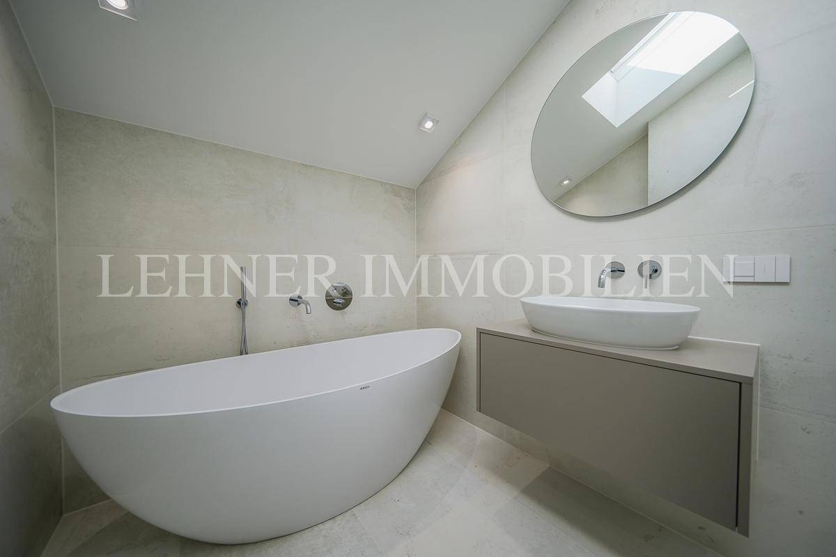 Elegantes Badezimmer mit ovaler Badewanne, modernem Waschtisch und großem Spiegel.