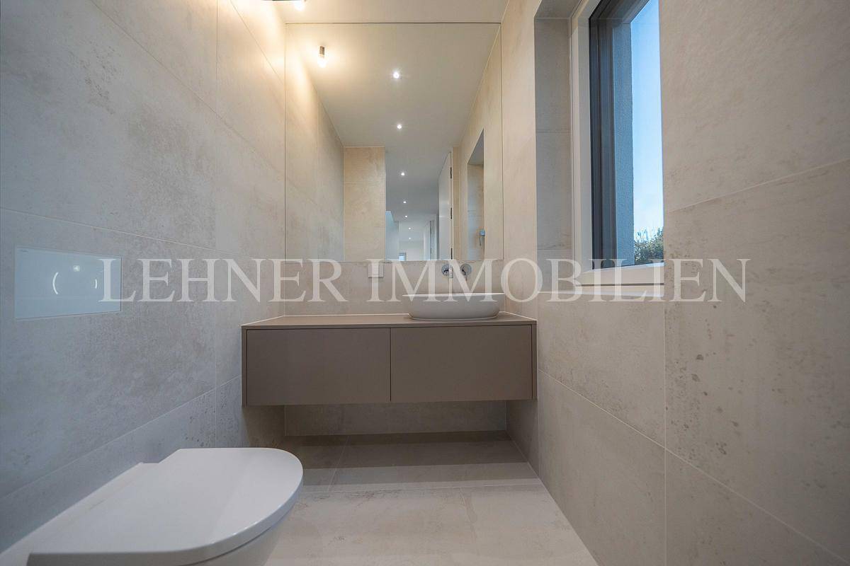 Modernes Badezimmer mit großformatigen Fliesen, schwebendem Waschtisch und Wand-WC.
