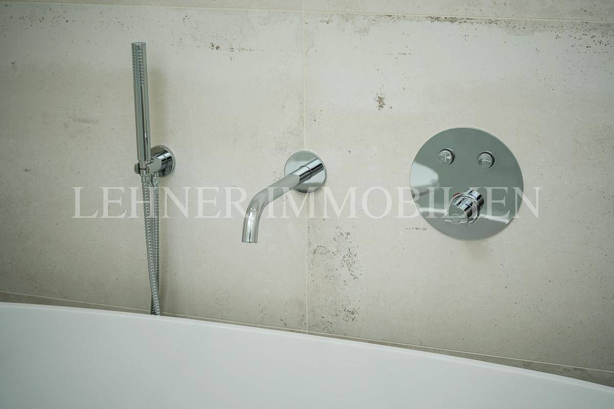 Detailaufnahme der modernen Armaturen über der Badewanne im Badezimmer.