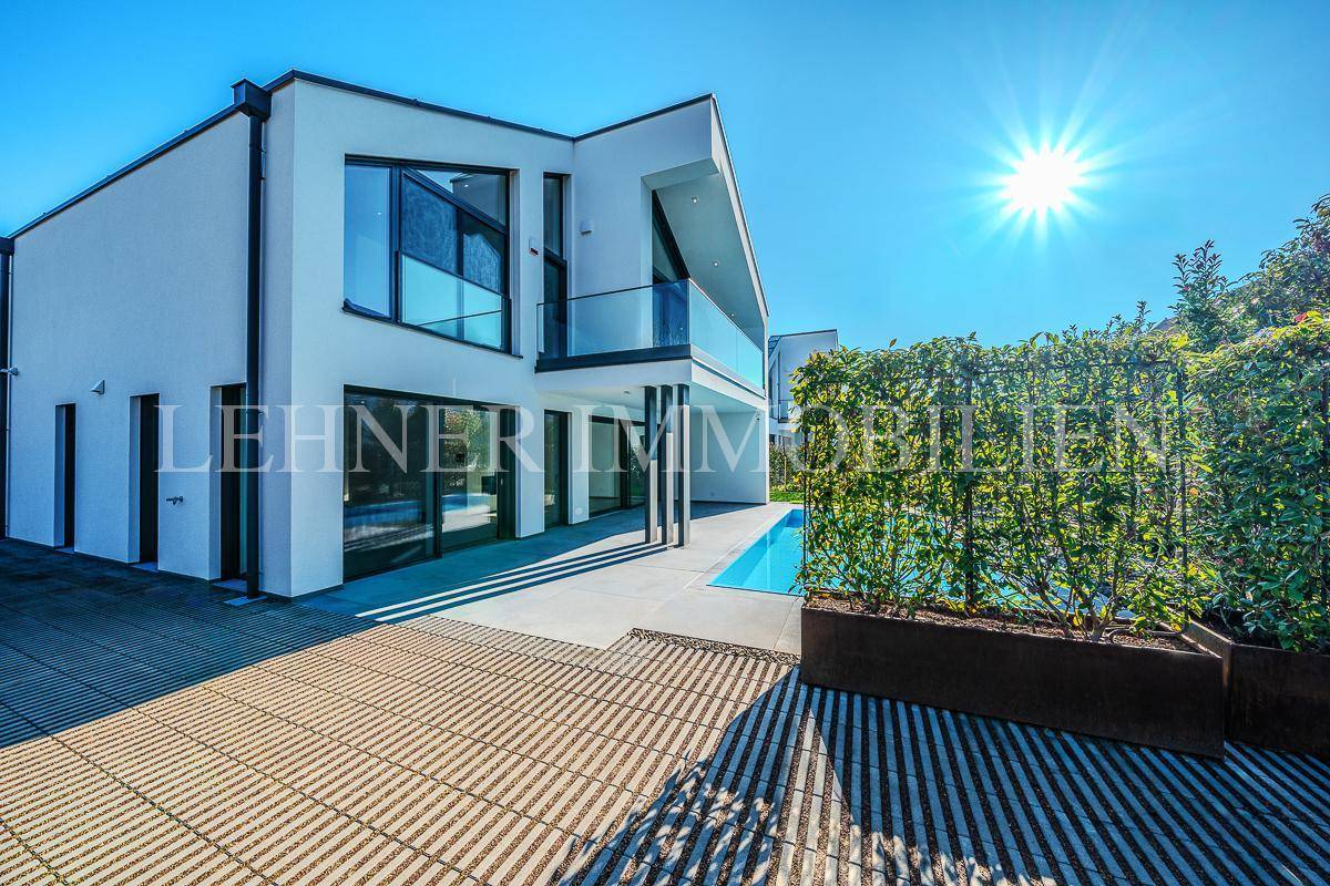 Sonniger Terrassenbereich mit moderner Pflasterung und Blick auf die elegante Villa.