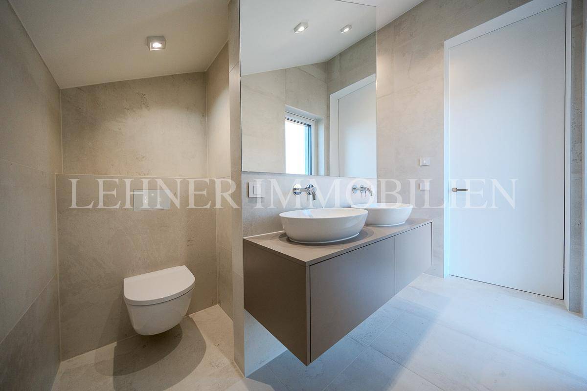 Elegantes Badezimmer mit Doppelwaschbecken, wandhängendem WC und großem Spiegel.