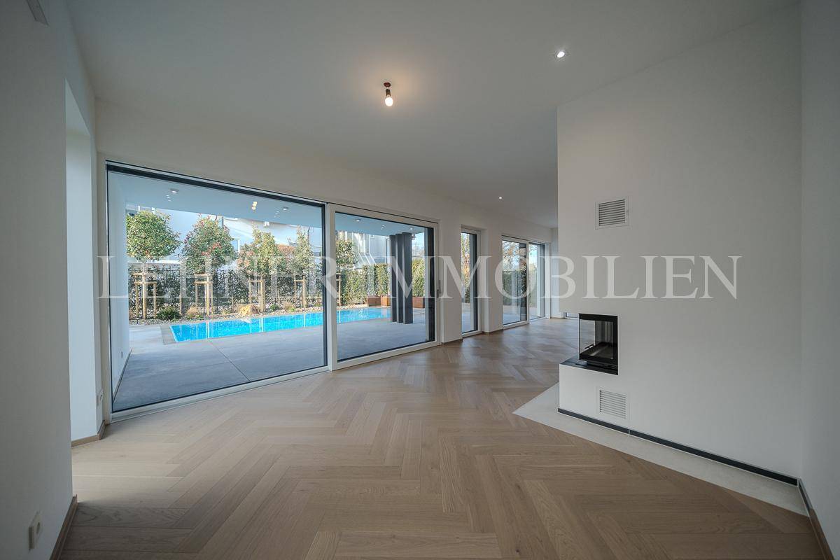 Weitläufiger Wohnraum mit großen Glasfronten, die den Blick auf den Außenbereich mit Pool ermöglichen.
