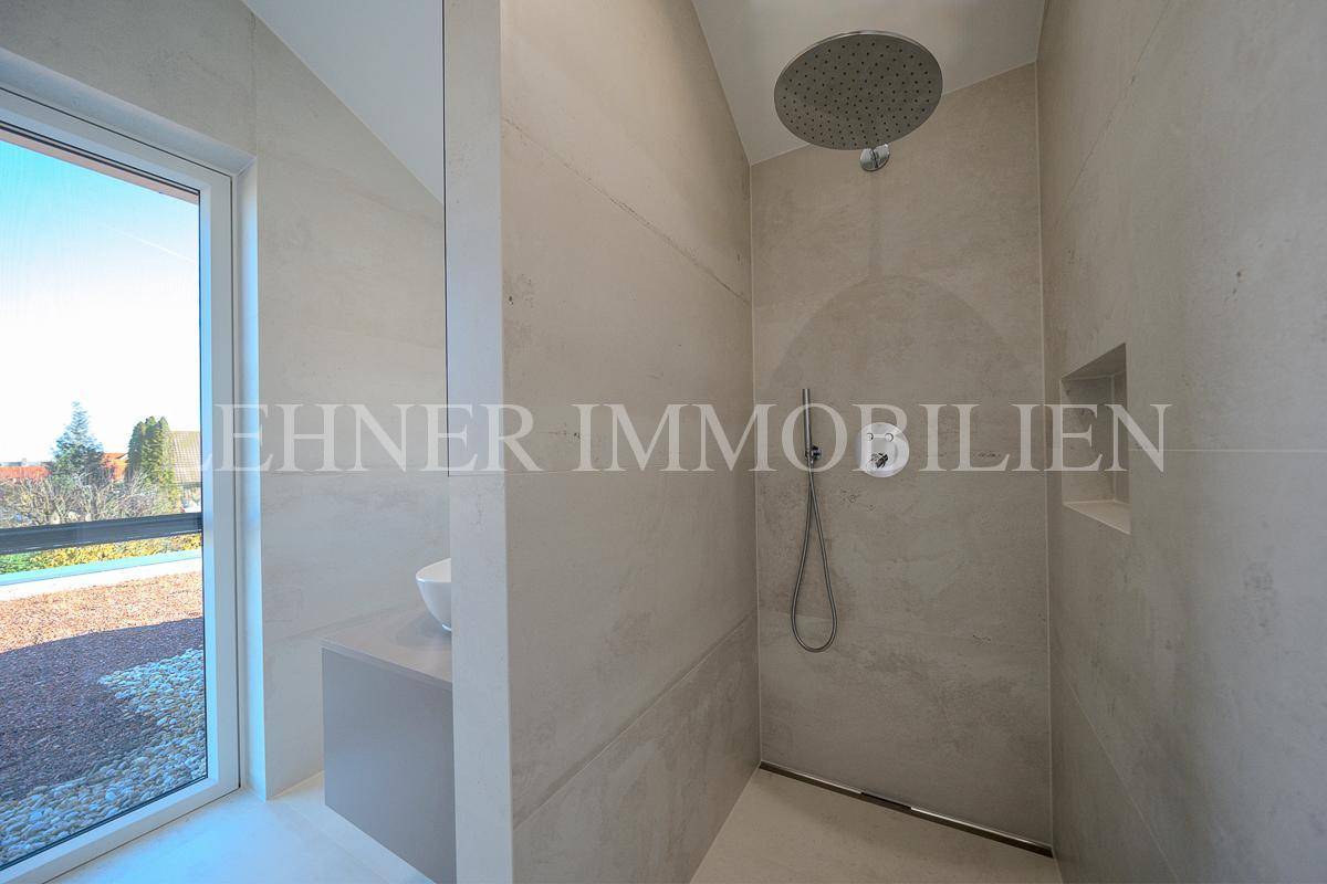 Geräumige Dusche mit Regenduschkopf und Handbrause, umgeben von hellen Fliesen und Fenster.