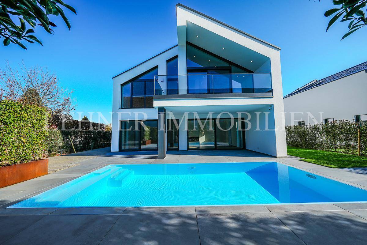 Strahlende moderne Villa mit großem Swimmingpool und klarem blauen Himmel an einem sonnigen Tag.