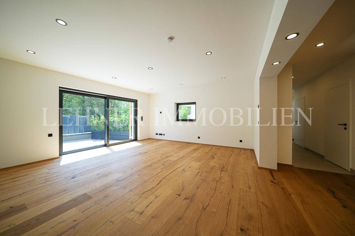 Lichtdurchflutetes Wohnzimmer mit Holzboden und Zugang zur Terrasse, modern und geräumig.