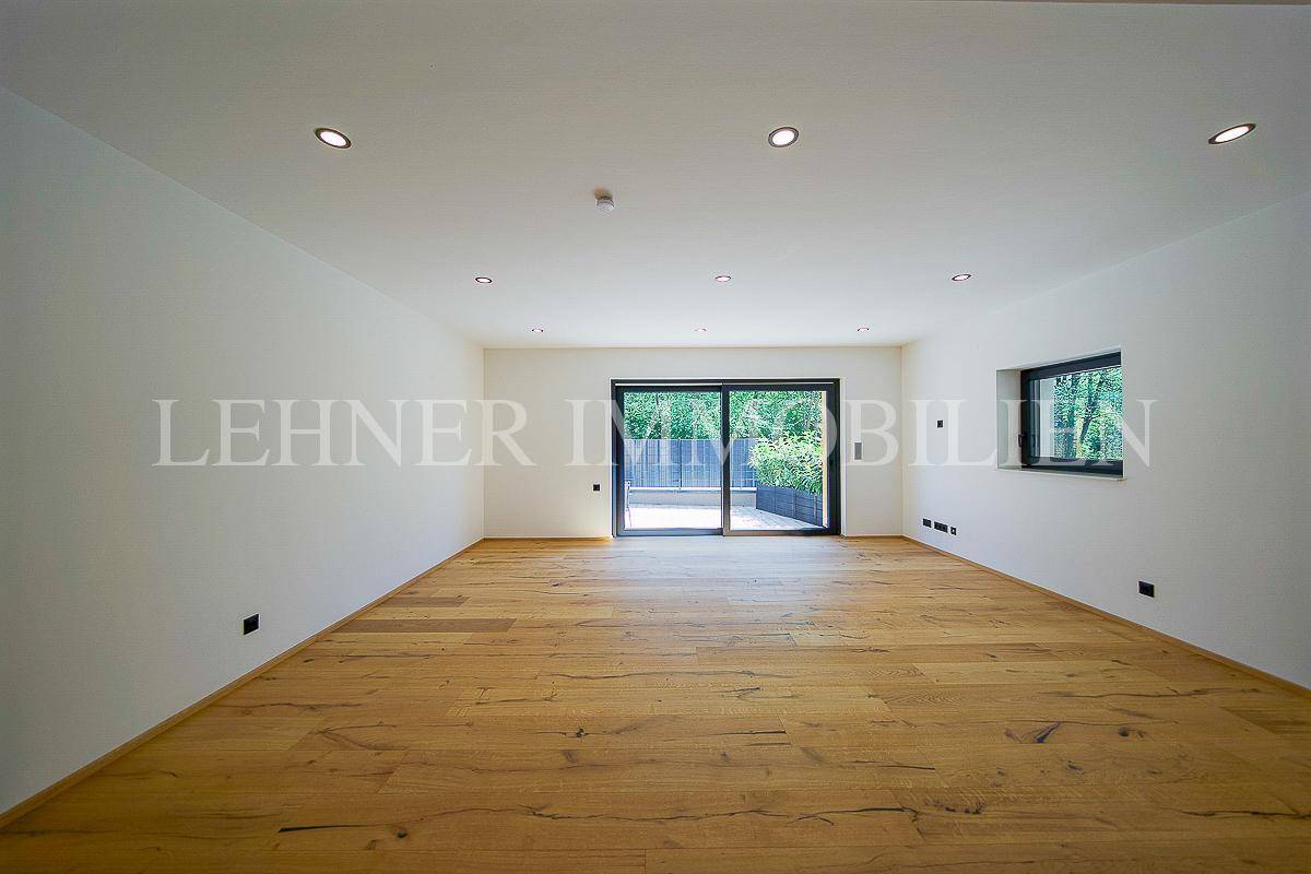 Helles Wohnzimmer mit Holzboden und großem Schiebefenster zum Außenbereich, lichtdurchflutet.