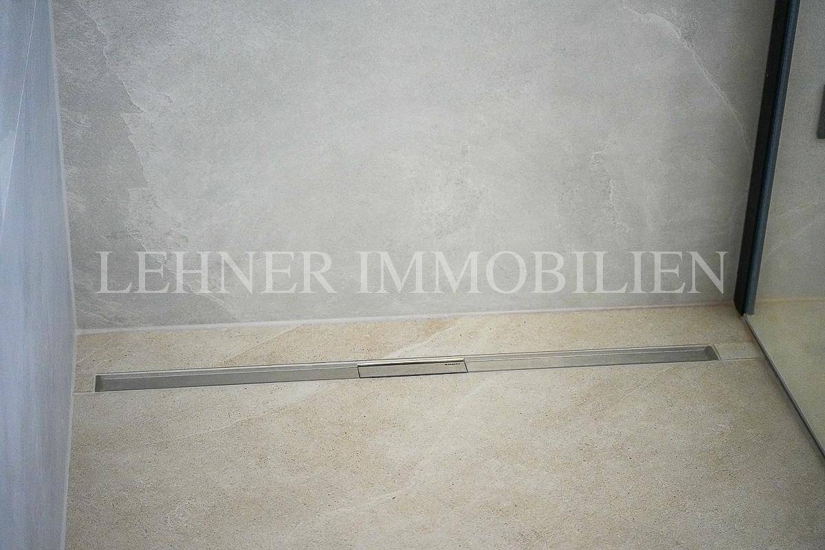 Detailansicht des modernen Duschbereichs mit bodengleicher Dusche und eleganten Fliesen.