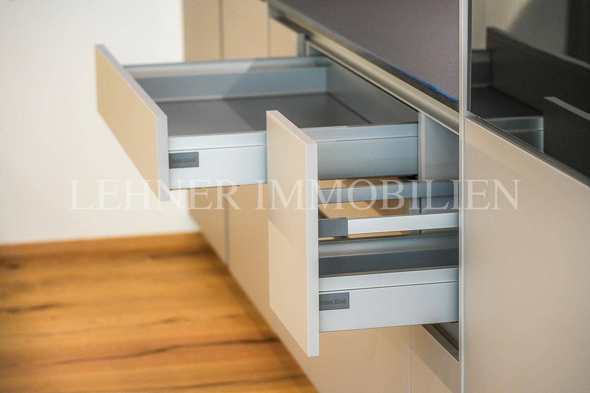 Detailansicht von modernen Küchenschubladen in Beige mit Soft-Close-Funktion und Holzboden.