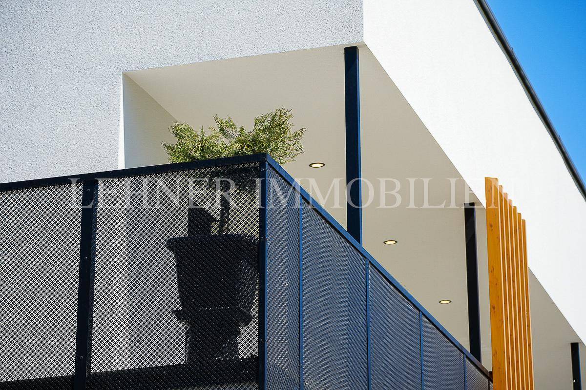 Detailansicht eines modernen Balkons mit schwarzem Metallgeländer und minimalistischer Bepflanzung.