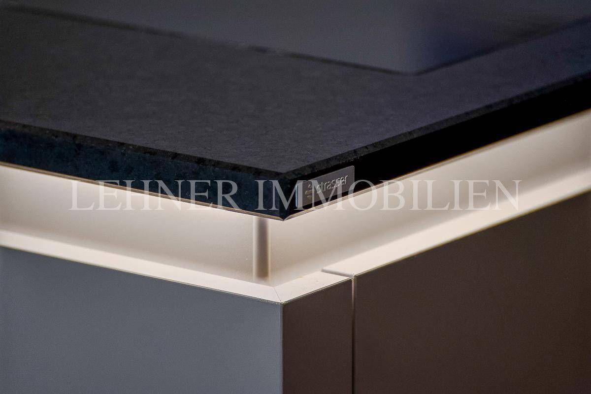 Nahaufnahme einer modernen Küchenarbeitsplatte in Schwarz mit integrierter Beleuchtung und minimalistischem Design.
