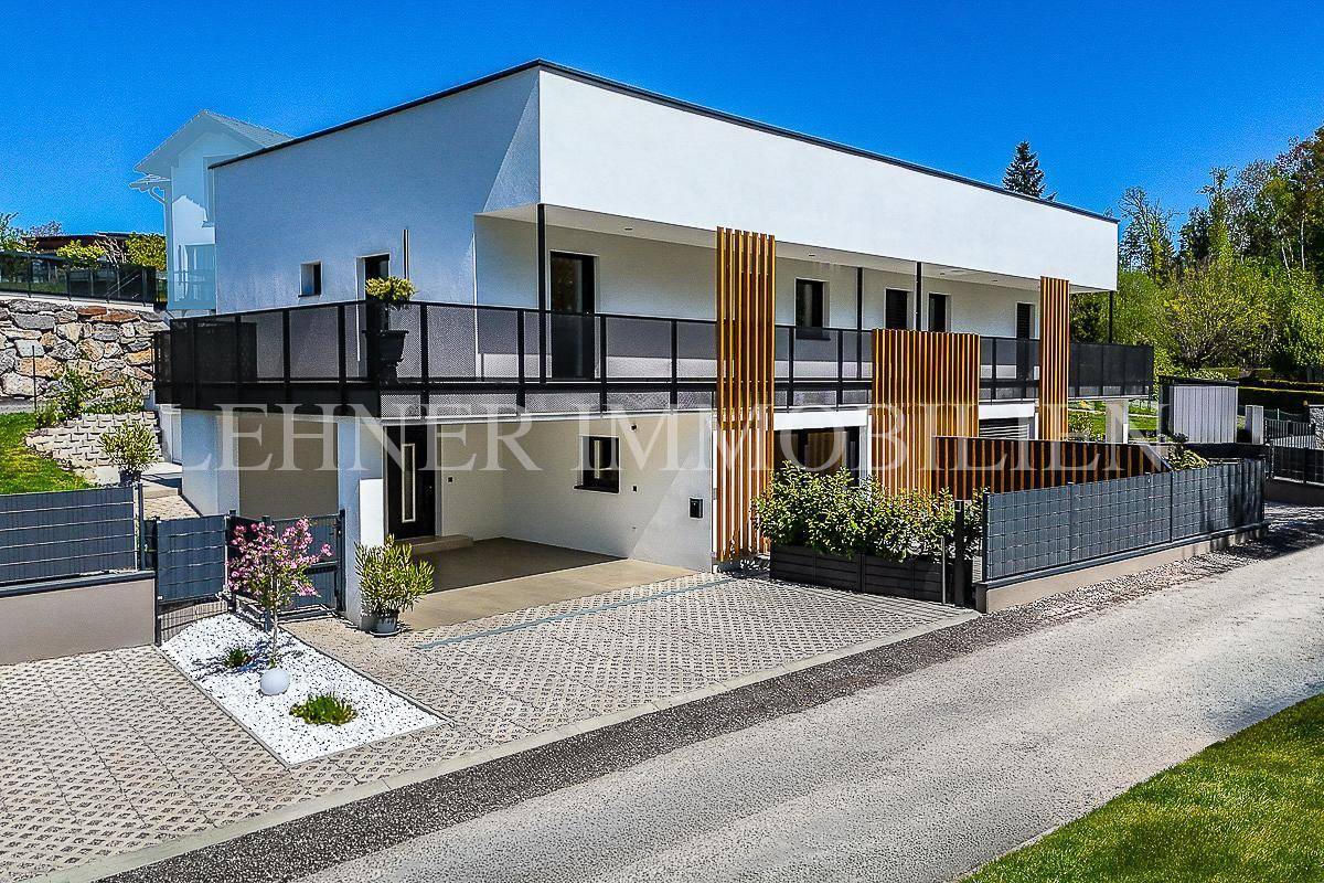 Modernes Mehrfamilienhaus bei Tag mit weißer Fassade und Balkonen, umgeben von Grünflächen.