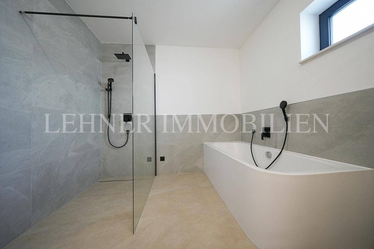 Modernes Badezimmer mit begehbarer Dusche, Badewanne und eleganten grauen Fliesen.