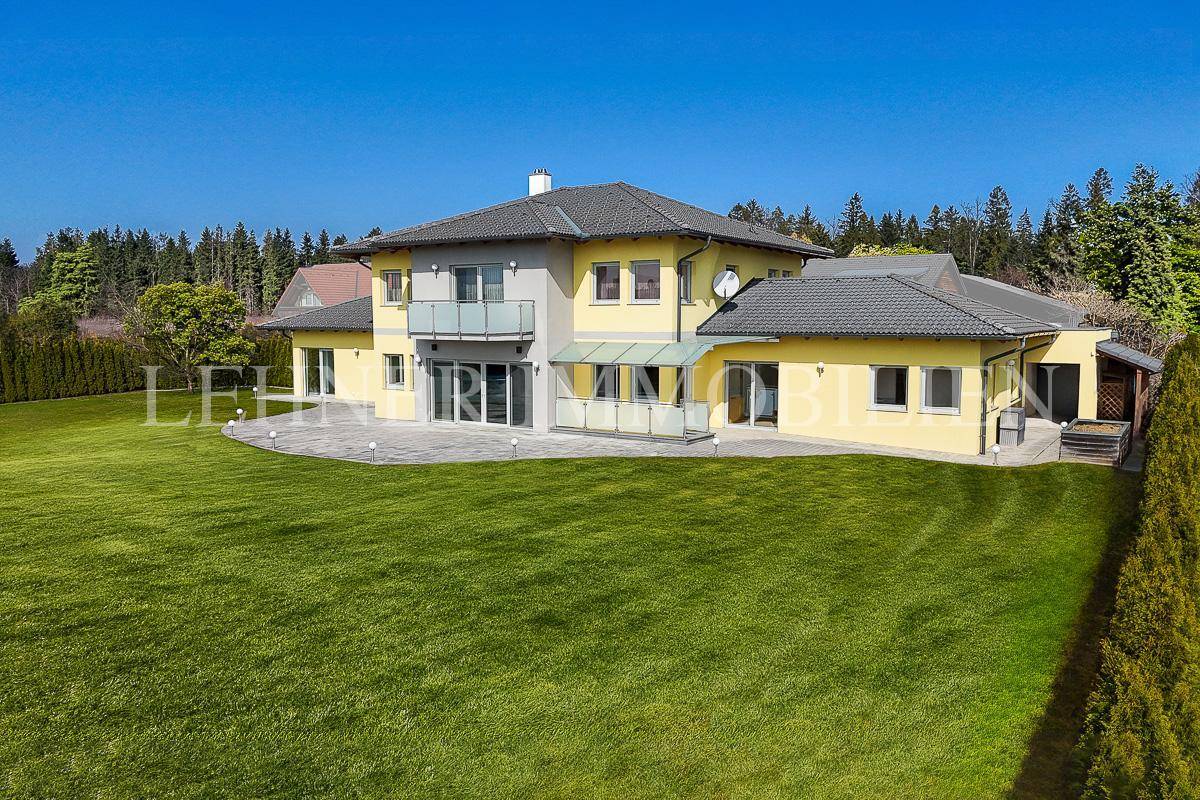 Weitläufiger Gartenbereich um das moderne Einfamilienhaus mit gelber Fassade und Balkon.