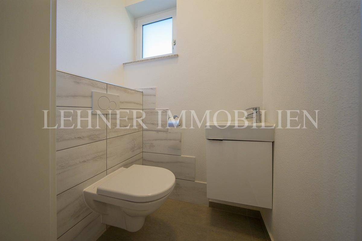 Modernes Gäste-WC mit wandhängender Toilette, kleinem Waschbecken und Fenster für Tageslicht.