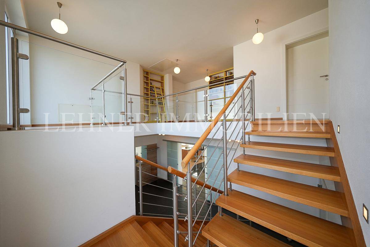 Offener Treppenaufgang mit Glasgeländer und Blick auf die untere Etage.