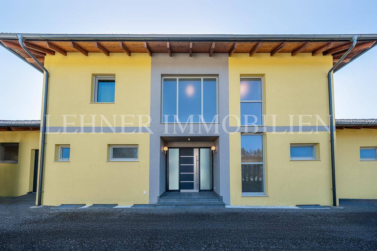 Moderne Hausfassade mit großzügigem Eingangsbereich und großen Fenstern.