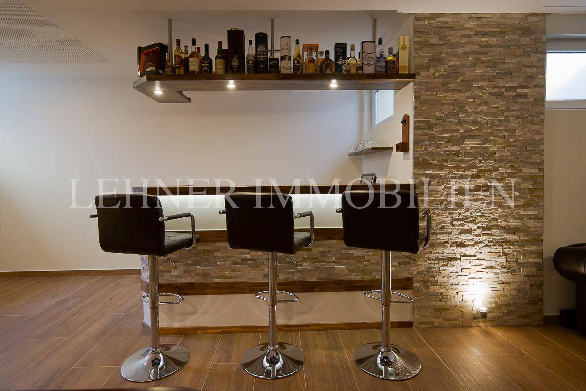Moderne Bar mit Barhockern und beleuchtetem Regal in einem Hobbyraum.