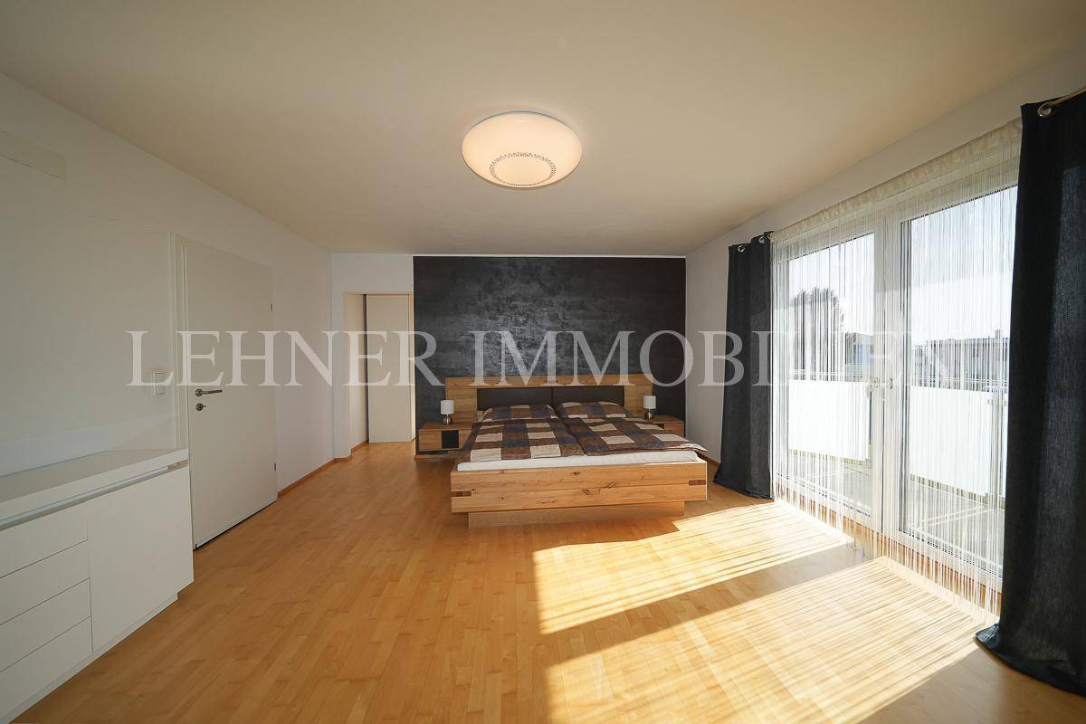 Helles Schlafzimmer mit Holzboden, großem Fenster und integrierten Schränken.