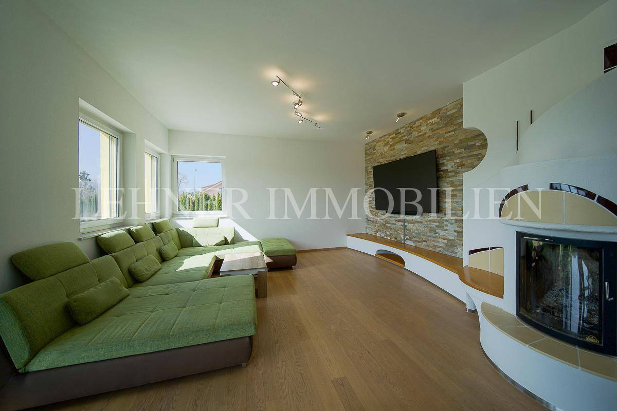 Helles Wohnzimmer mit großem grünen Sofa, Kamin und Steinwand.