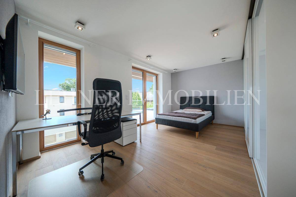Helles Arbeitszimmer mit Schreibtisch, Bürostuhl und Bett, ideal für Home-Office.
