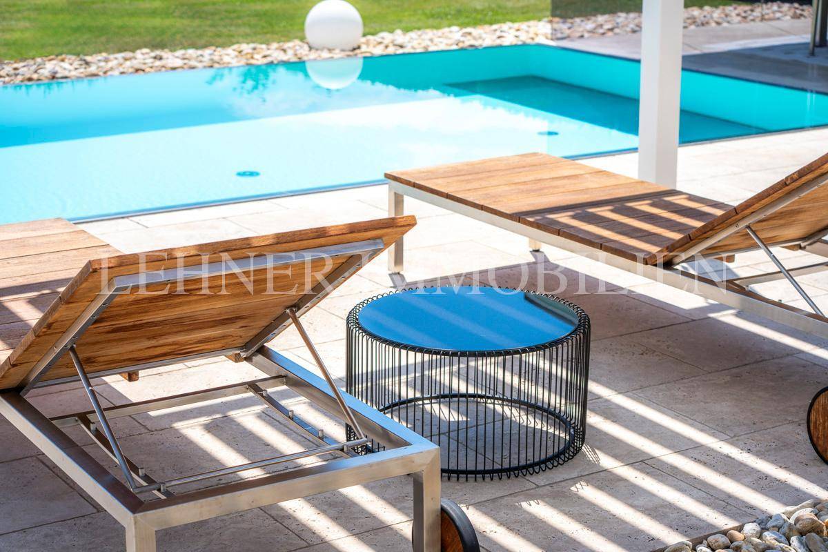 Liegebereich am Pool mit modernen Sonnenliegen und Beistelltisch.