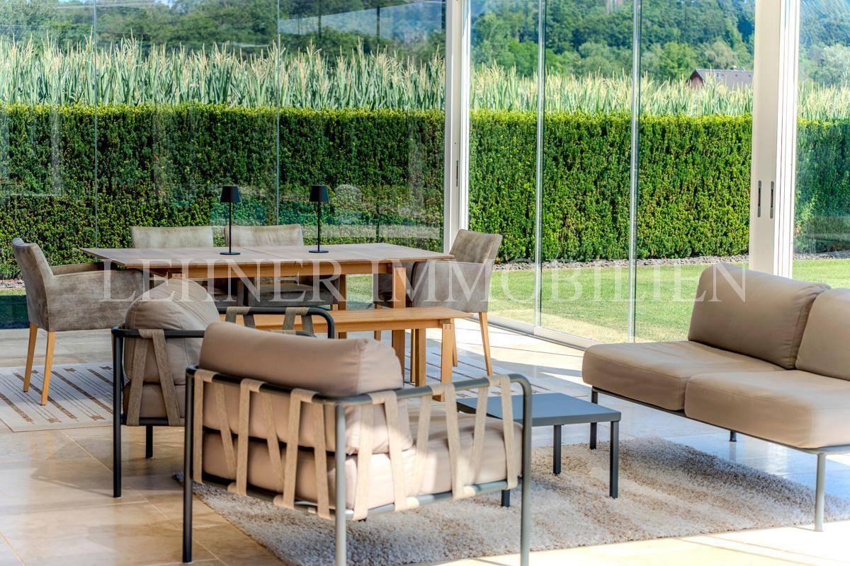 Gemütlicher Loungebereich im Wintergarten mit Blick auf den Garten.