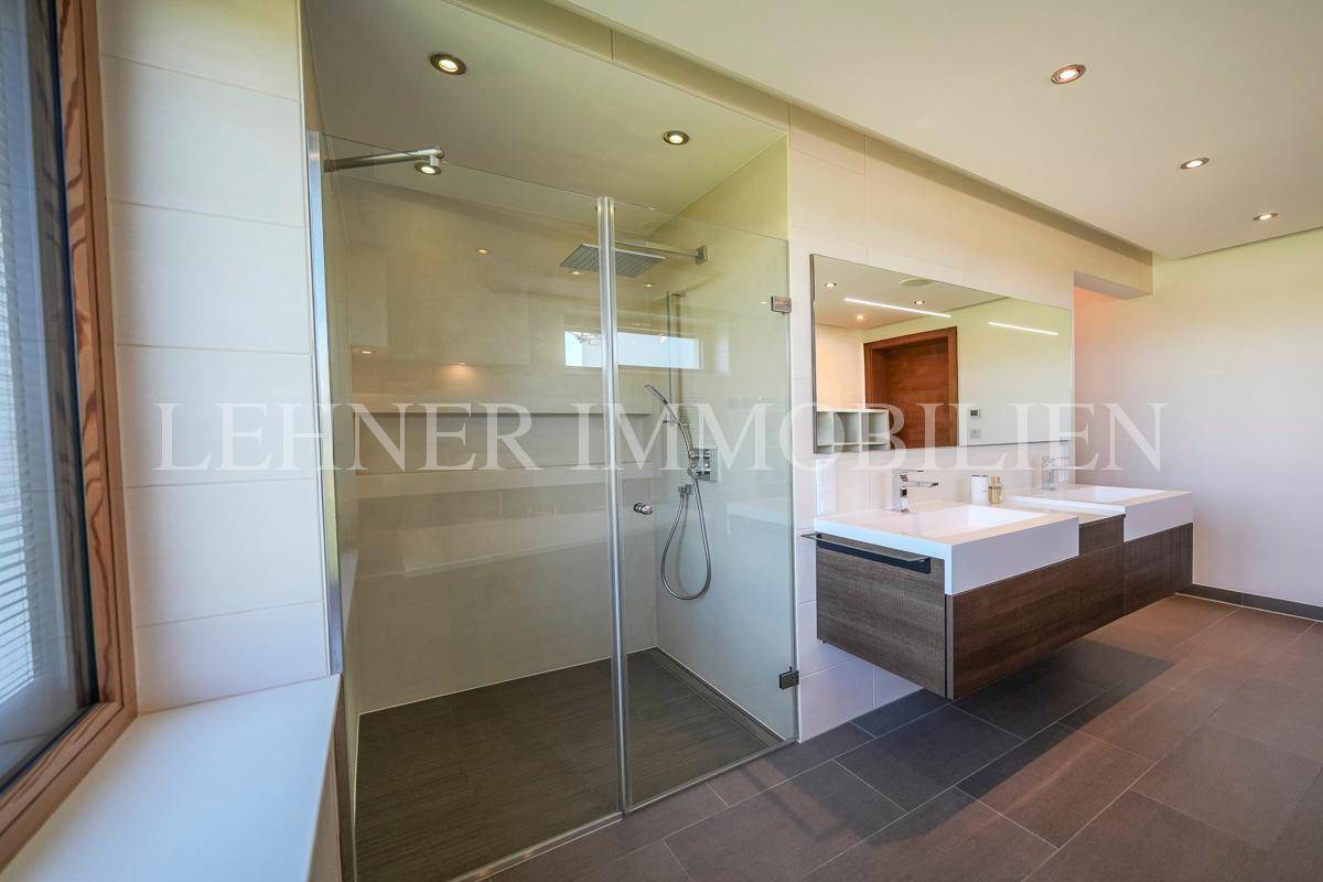 Geräumiges Badezimmer mit begehbarer Dusche, Doppelwaschbecken und großem Spiegel.
