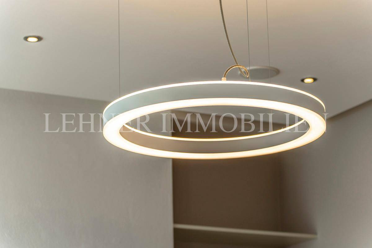 Nahaufnahme einer modernen, runden LED-Pendelleuchte, die den Raum stilvoll beleuchtet.