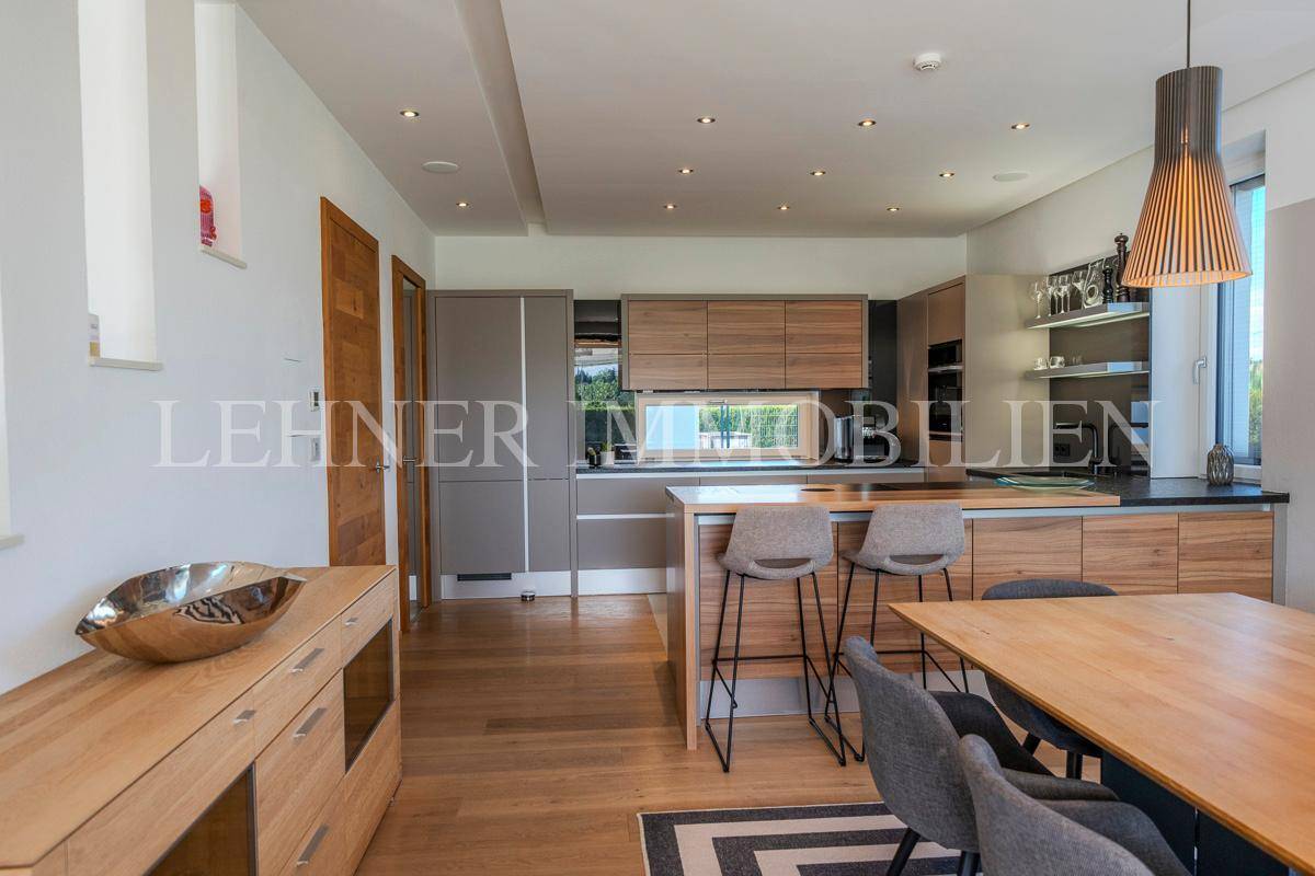 Moderne Einbauküche mit Holzfronten, Kücheninsel und integrierten Geräten im offenen Wohnbereich.