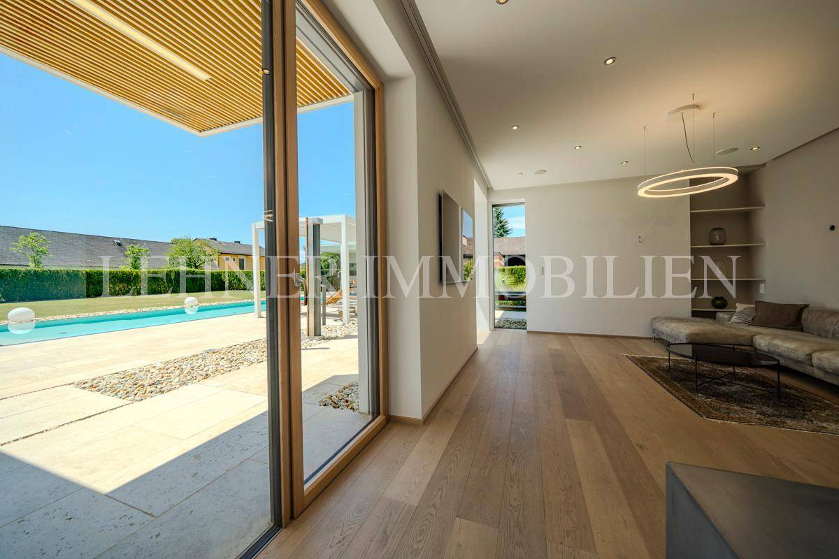 Helles Wohnzimmer mit großen Glasschiebetüren, die zum Poolbereich und Garten führen.