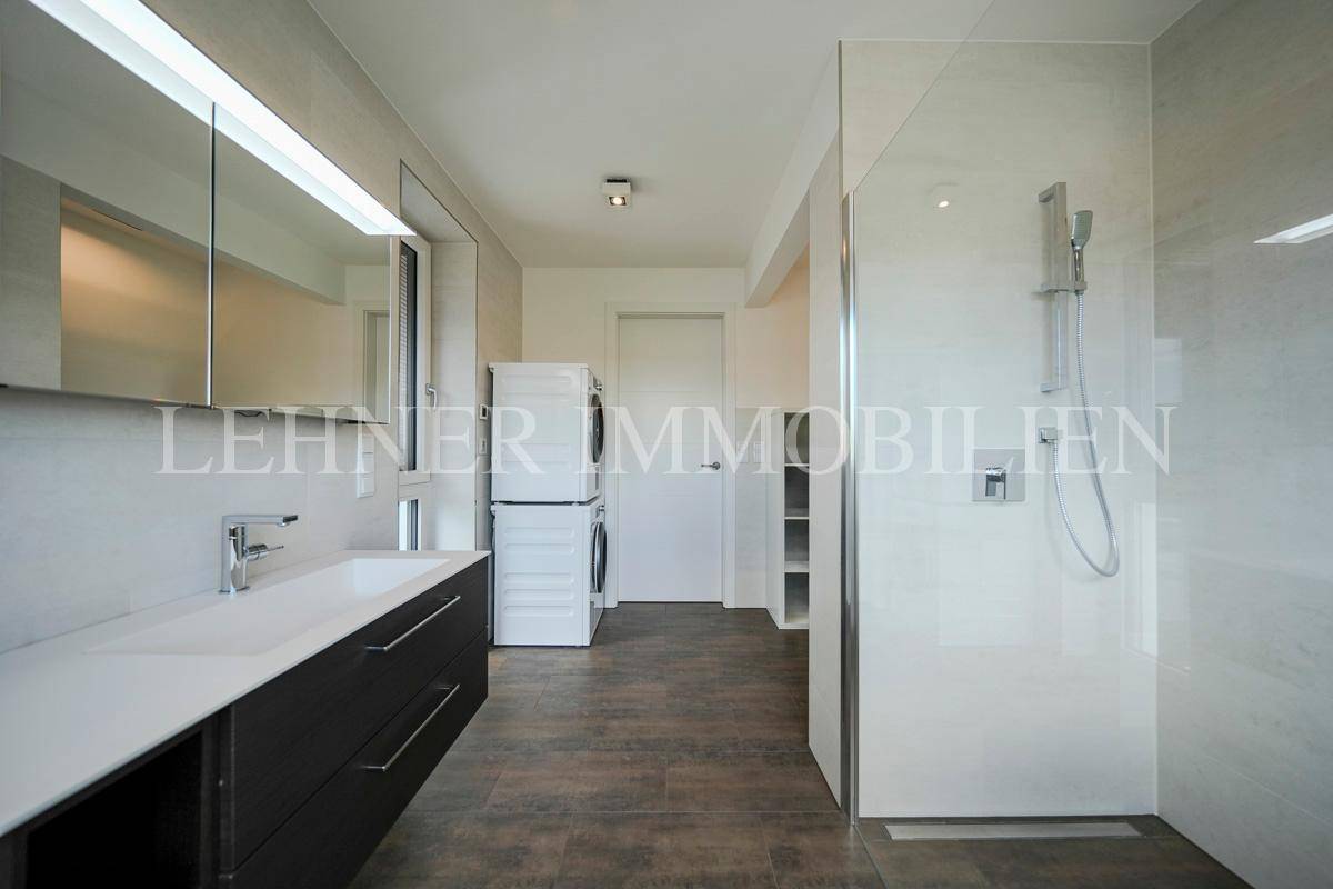 Helles Badezimmer mit begehbarer Dusche, Waschbecken und integriertem Wäschebereich.