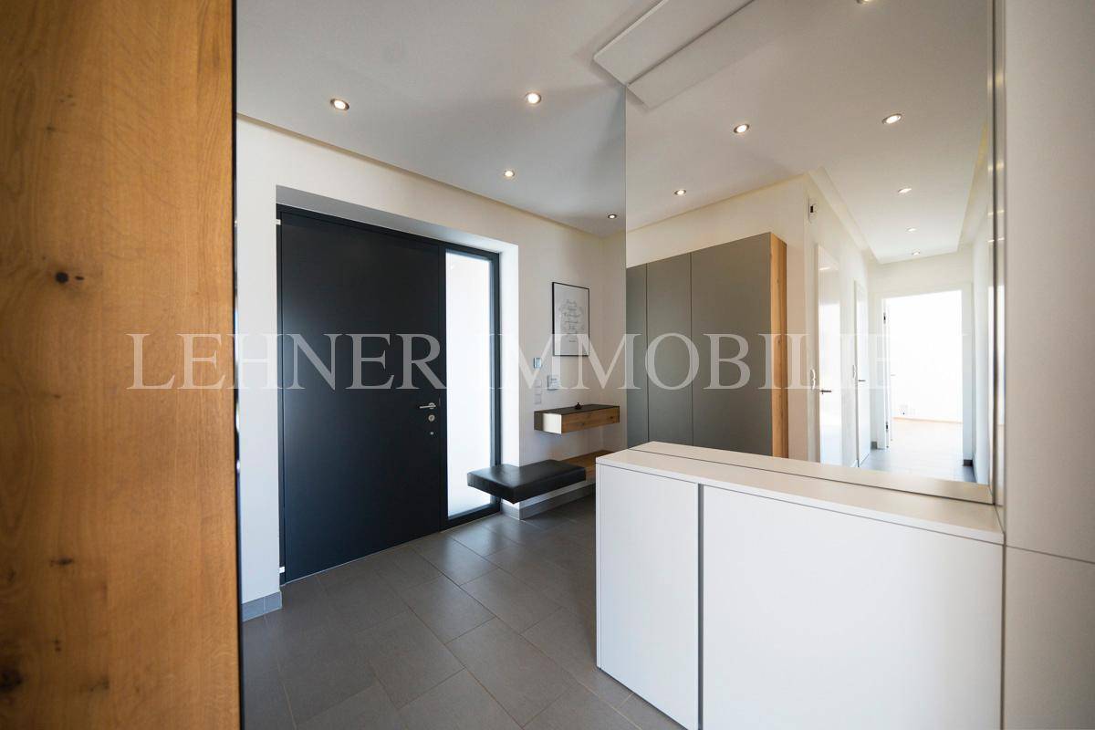Moderner Flur mit Fliesenboden, Einbauschränken und einem großen Spiegel, der den Raum erweitert.