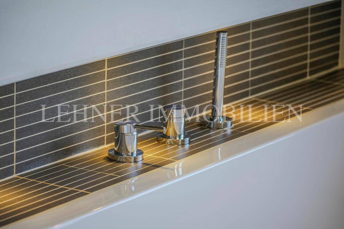 Nahaufnahme der glänzenden Badewannenarmaturen mit integrierter Handbrause.