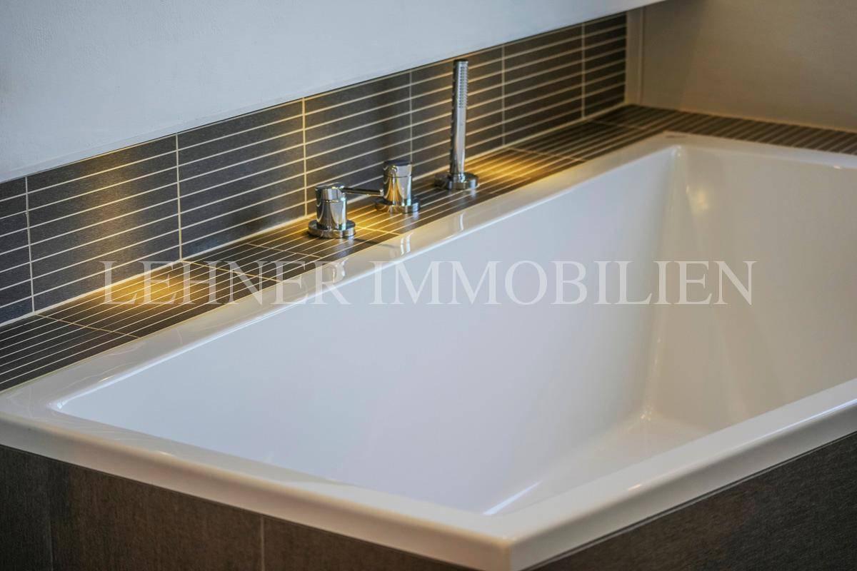 Detailaufnahme der modernen Badewanne mit eleganten Armaturen und Fliesenakzenten.