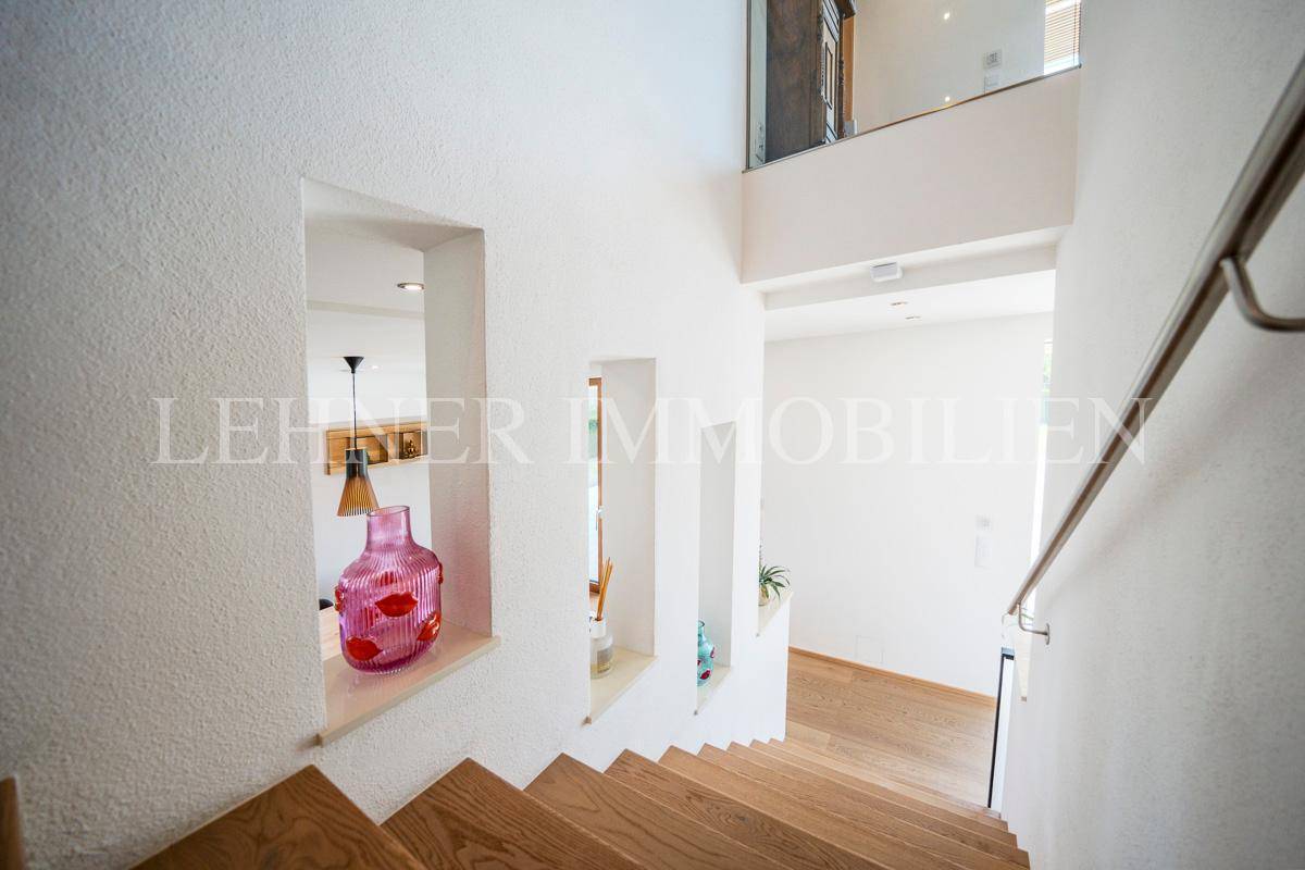 Treppenhaus mit weißen Wänden und dekorativen Nischen, das in die untere Etage führt.