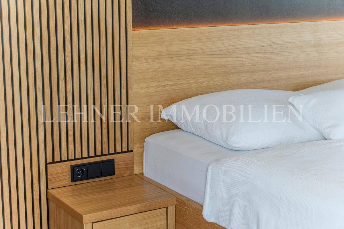 Nachttisch mit Steckdosen und Holzwandverkleidung neben dem Bett im modernen Schlafzimmer.