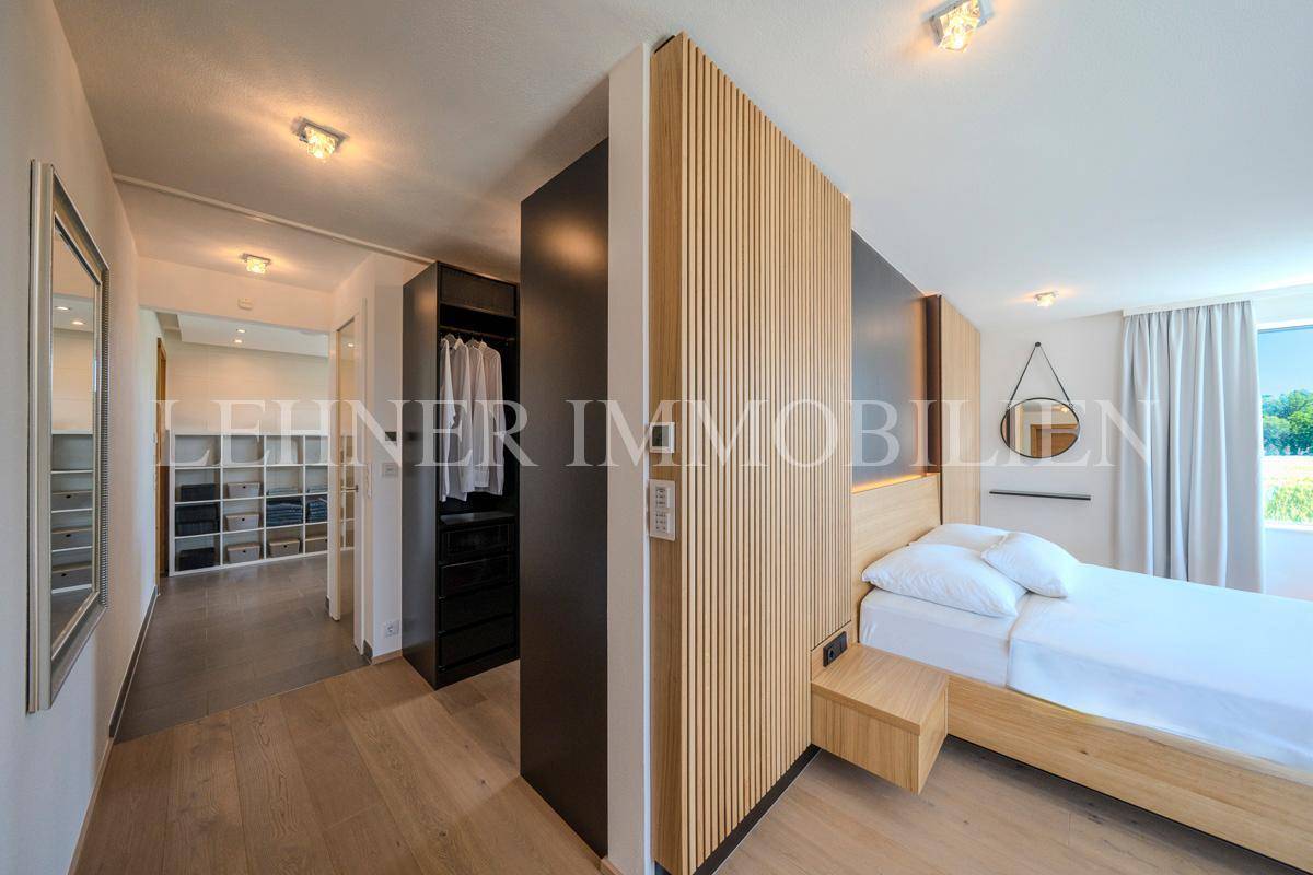 Schlafzimmer mit Holzwand und offenem Zugang zu einem begehbaren Kleiderschrankbereich.