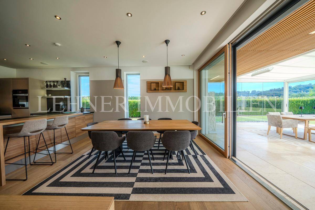 Offener Essbereich mit Holzboden und großzügigem Zugang zur verglasten Terrasse mit Gartenblick.