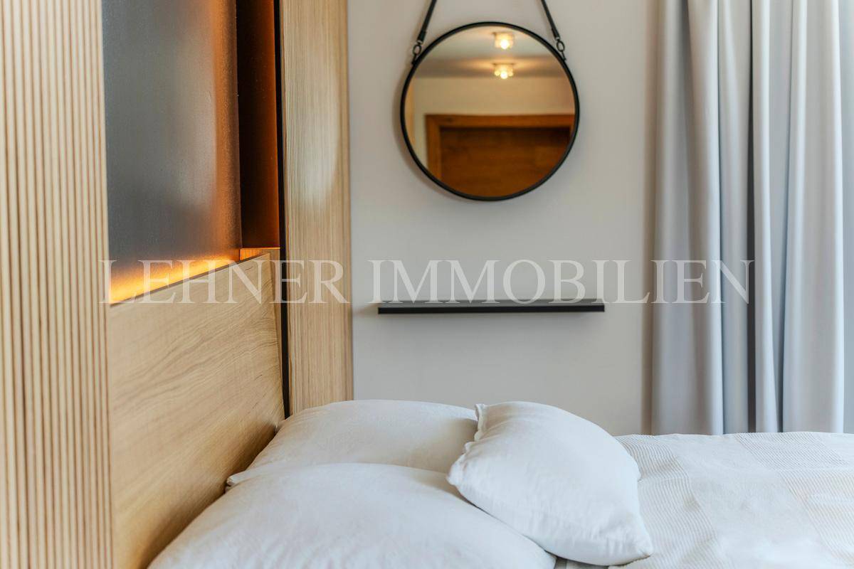 Detailansicht des Bettes mit modernem runden Spiegel und Holzwand im Schlafzimmer.