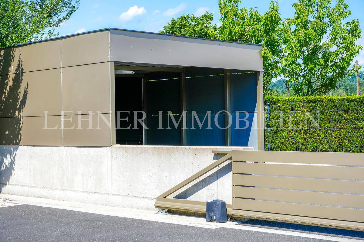 Moderner Carport mit automatischem Tor und Zugang zum Grundstück.