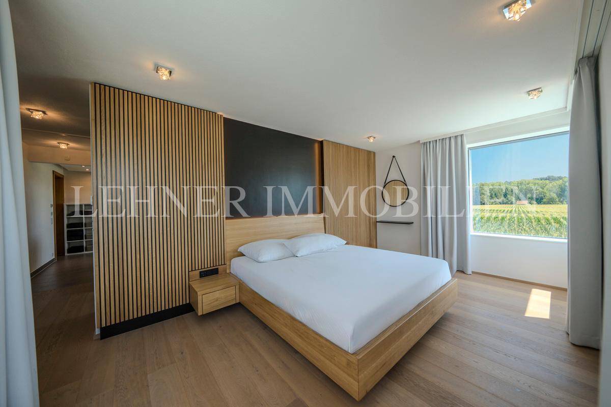 Helles Schlafzimmer mit Holzelementen und Panoramafenstern, die einen weiten Blick bieten.