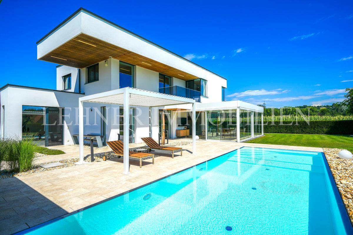 Großzügige Außenanlage der modernen Villa mit Swimmingpool, Liegebereich und weitläufigem Rasen.