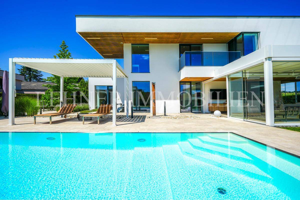 Nahaufnahme des Pools mit integrierter Treppe und der modernen Architektur der Villa bei Tageslicht.