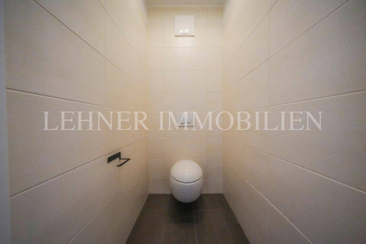 Schlichtes Gäste-WC mit Wand-WC und modernen Fliesen in hellem Farbton.