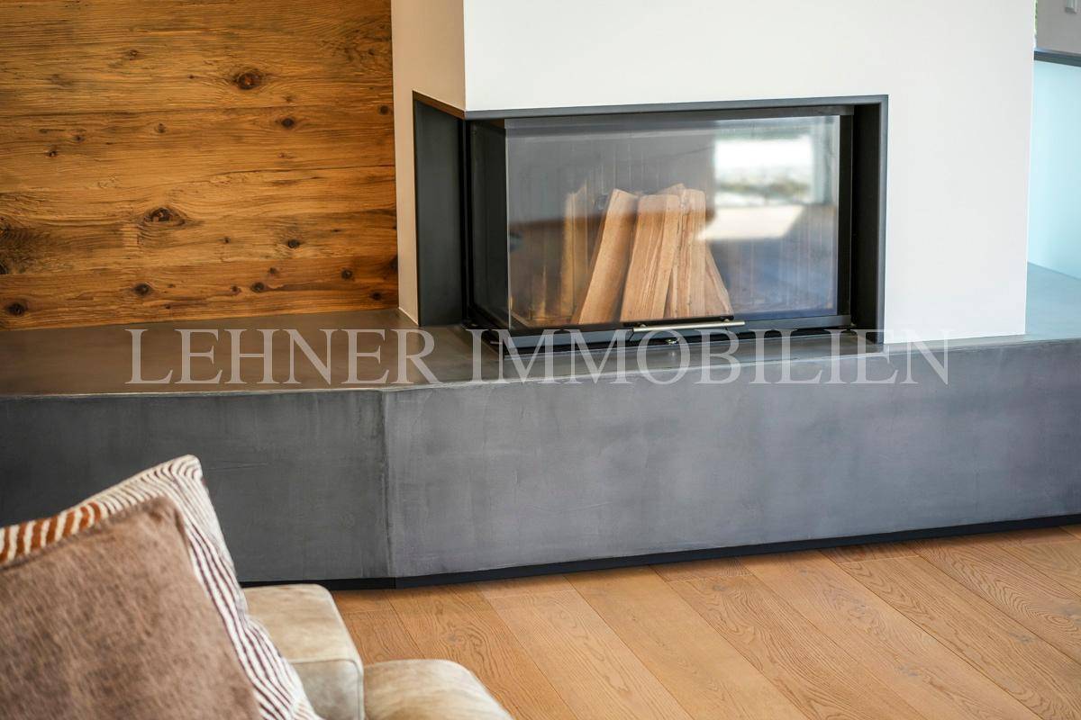 Moderner Kamin mit Holzscheiten und einer eleganten Betonverkleidung im Wohnbereich.