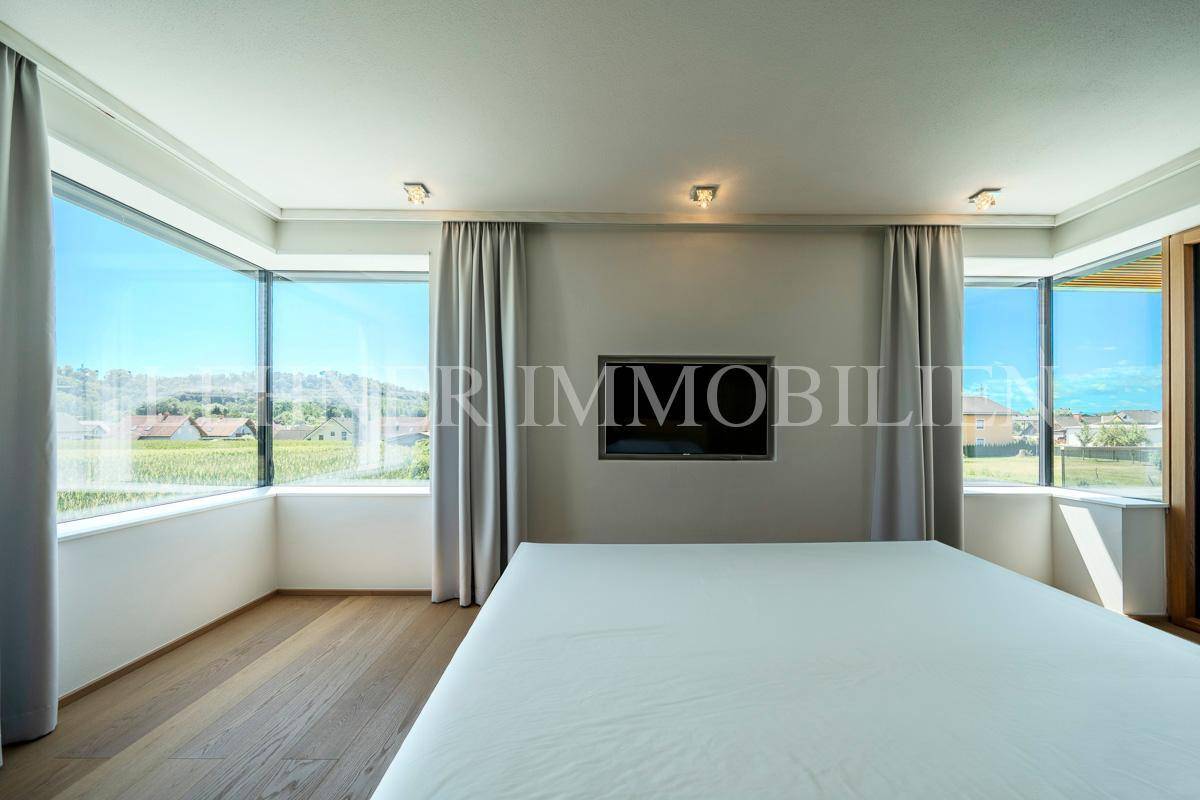 Schlafzimmer mit raumhohen Fenstern, die einen beeindruckenden Blick auf die Landschaft freigeben.